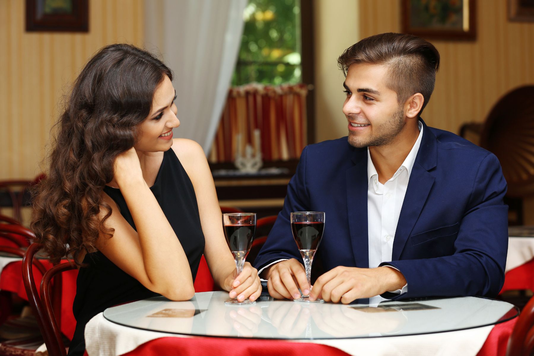 attractive young couple dating at the restaurant, sharing a drink and smiling at each other
