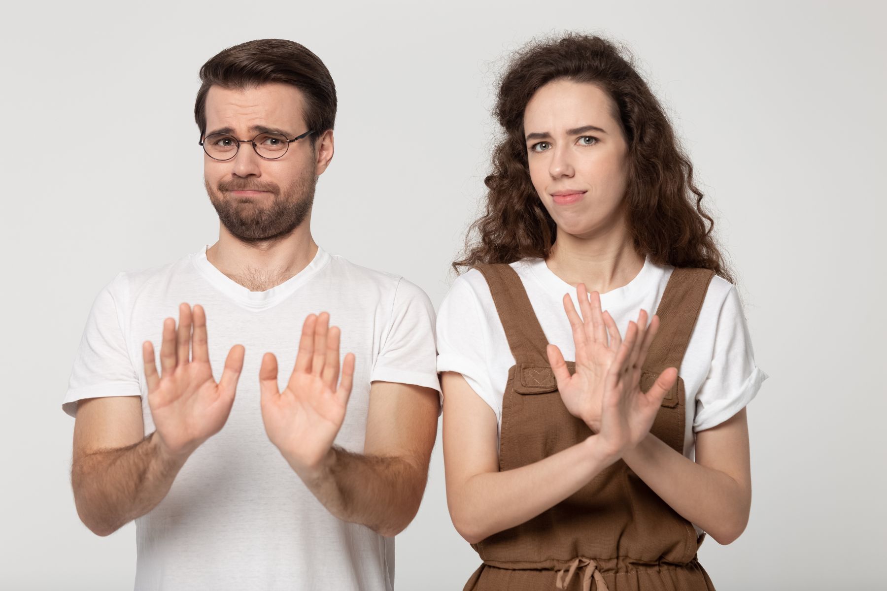 Displeased millennial couple isolated on grey studio background look at camera denying bad sale offer, dissatisfied unhappy man and woman make gesture say no reject refuse proposal or suggestion
